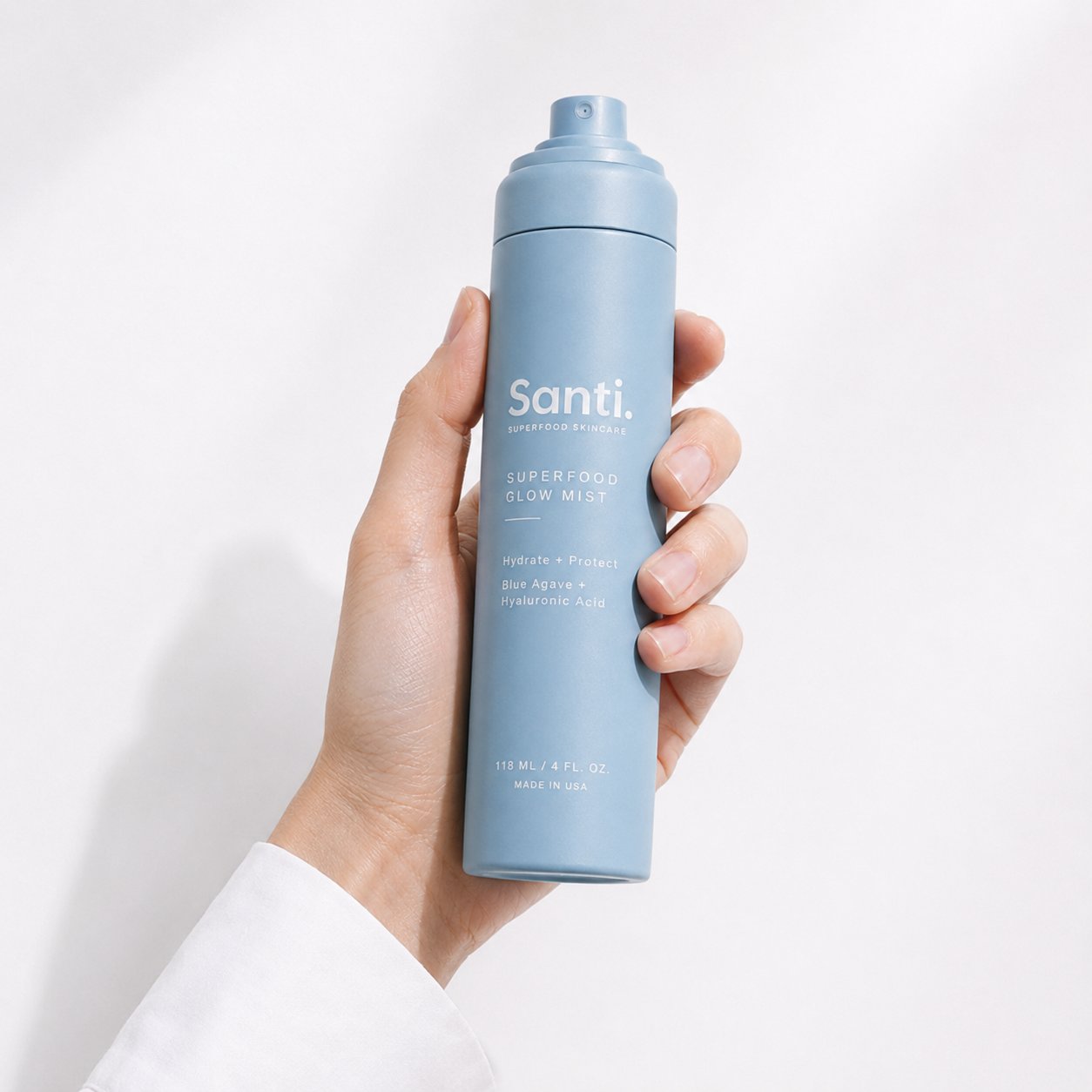 Hand holding the Santi Superfood Glow Mist against a soft white background